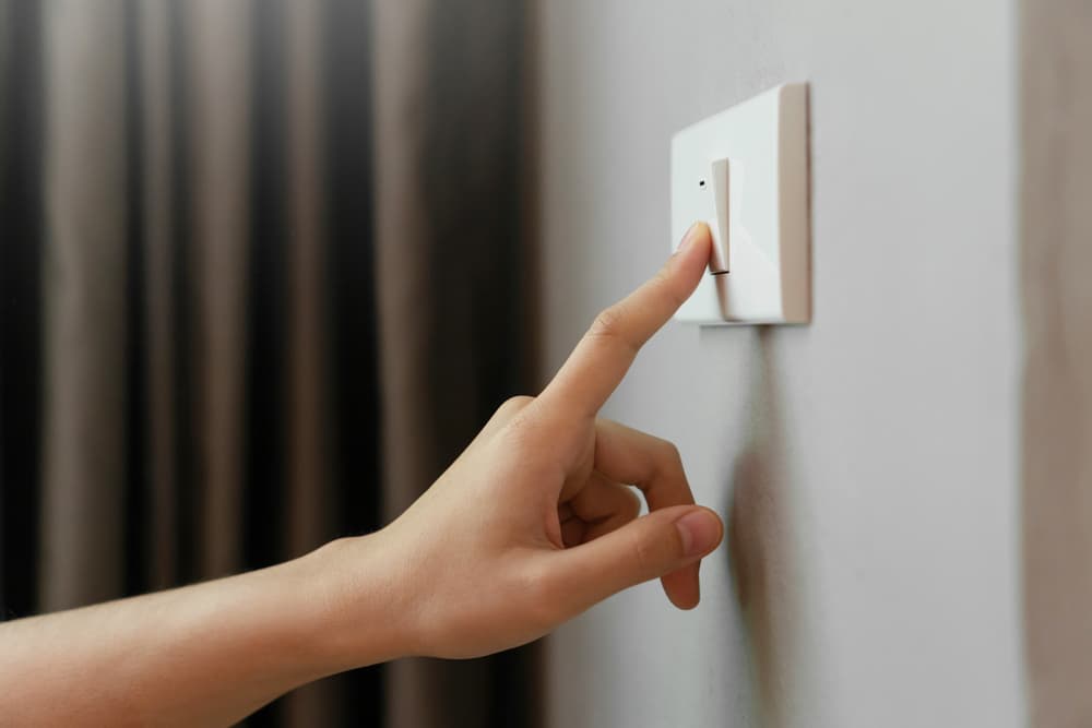 Hand turning off light switch